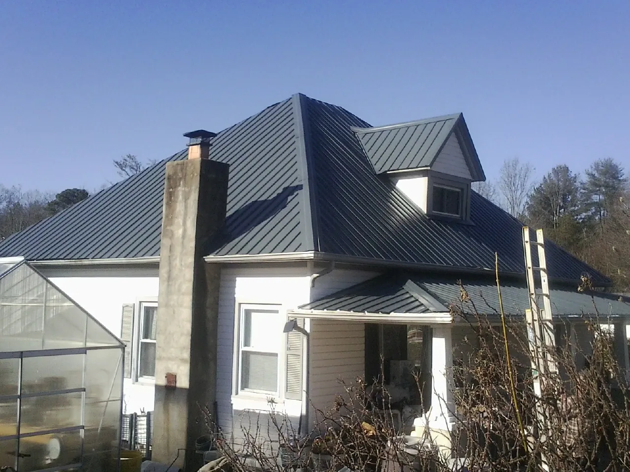 Dark blue standing seam metal roof on a white farmhouse with dormer — Slate & Tile Roof Repair by Roofing Brothers in Yuba City