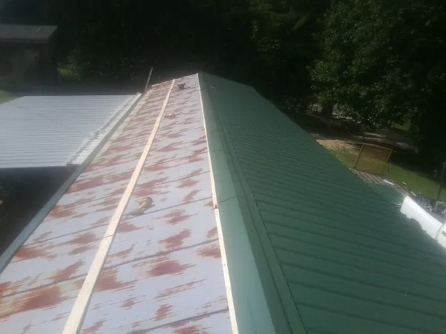 Old rusted panels beside newly installed green metal roofing — Wind Damage Roof Repair by Roofing Brothers in Yuba City