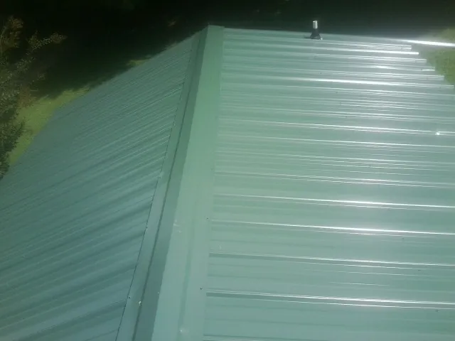 New green metal panels meeting at the ridge of a roof — Flat Roof Repair work by our crew in Yuba City