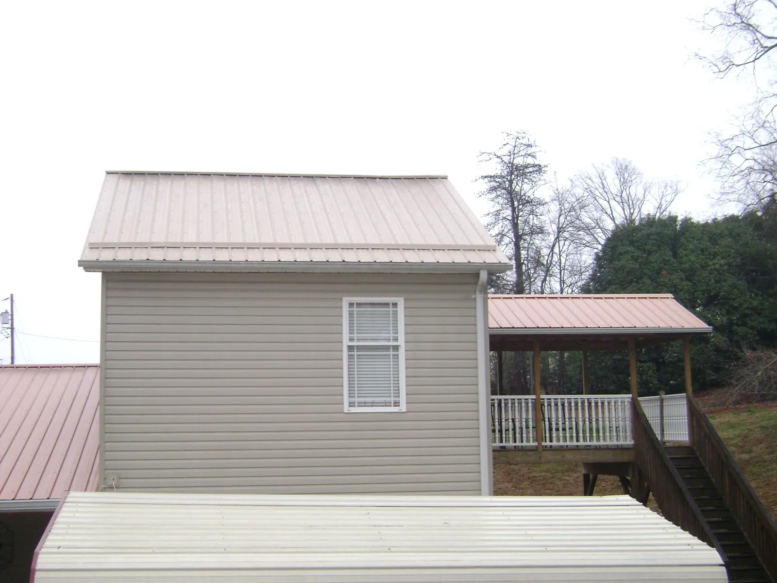 Tan metal roofs on a two story addition and attached porch, from a Roof Replacement job in Yuba City