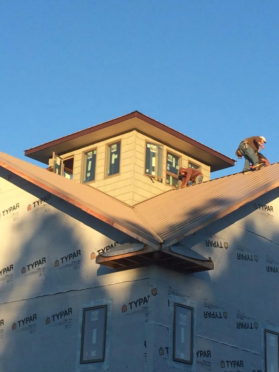 Roofers working around a rooftop cupola on a new metal roof at sunset — Roof Waterproofing in Yuba City by Roofing Brothers